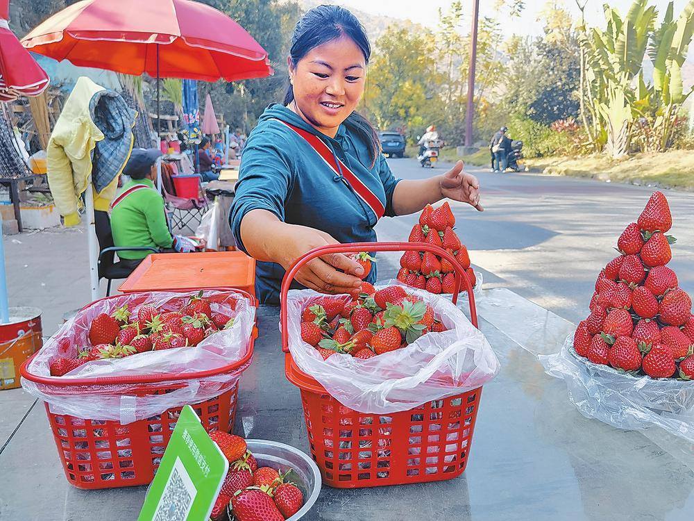 村民在集市上售卖草莓。